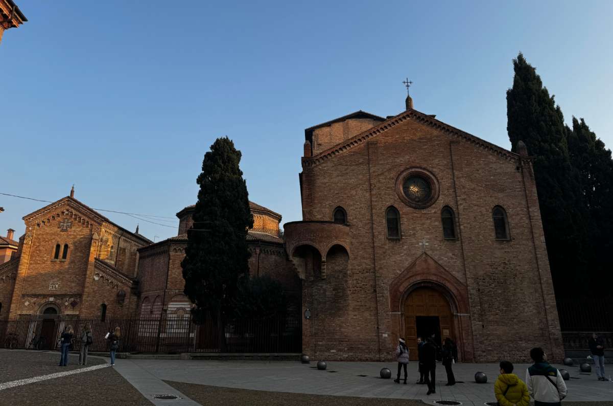 a photo of the brick churches of the Santo Stefano complex on their piazza in the late afternoon, Bologna, Italy, photo by Next Level of Travel