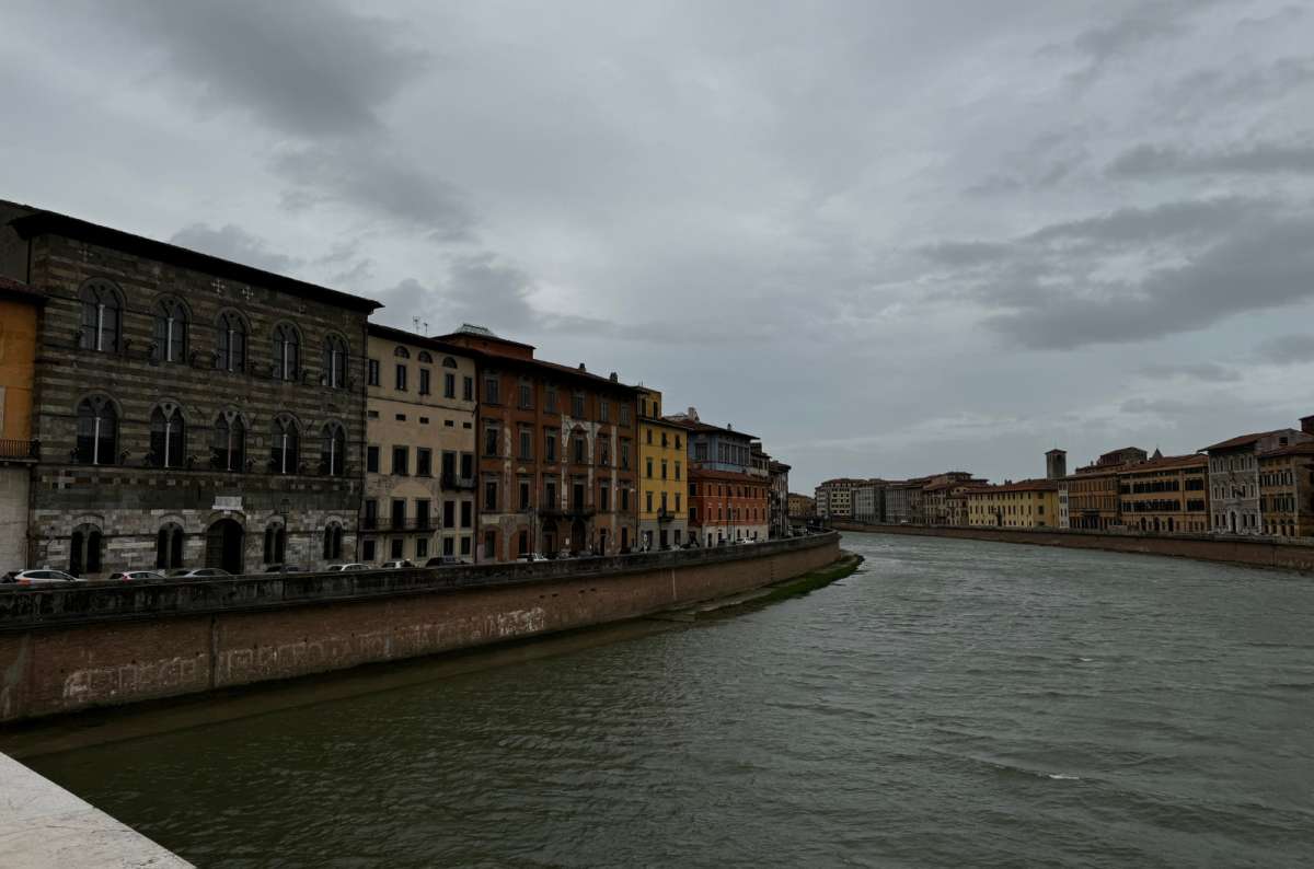 a photo of the colorful palazzi lining the Arno River under a cloudy sky, Pisa, Italy, photo by Next Level of Travel