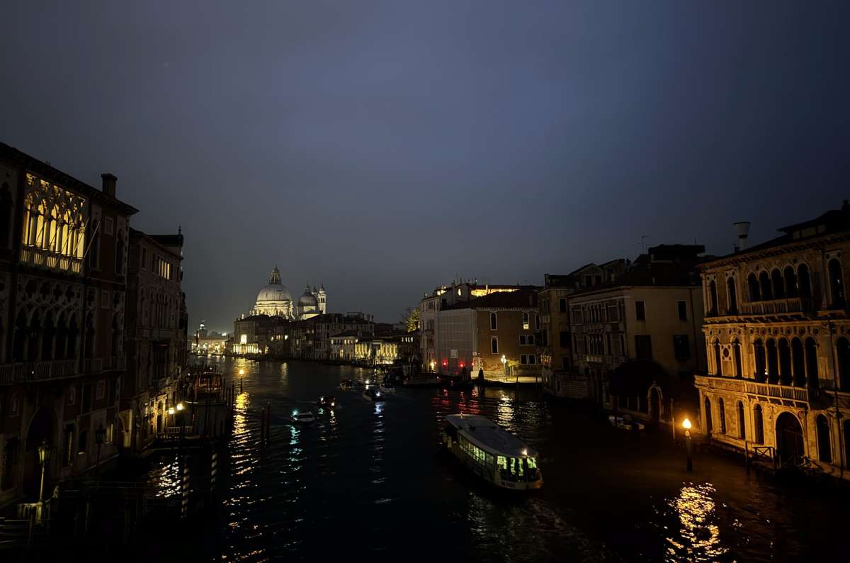a photo of the Grand Canal at dusk with the lit dome of Santa Maria della Salute at the end, Venice, Italy, photo by Next Level of Travel