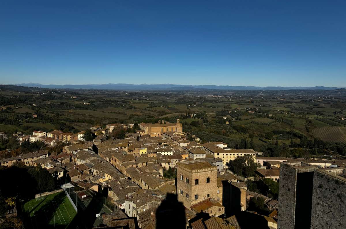 a photo of the rooftops of San Gimignano and the Tuscan countryside seen from the top of Torre Grossa, San Gimignano, Italy, photo by Next Level of Travel