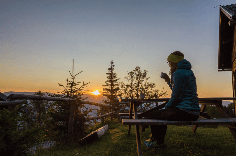 Woman drinking coffee in the mountains at sunrise