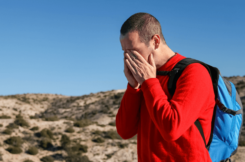 Man experiencing headache on the hike. 