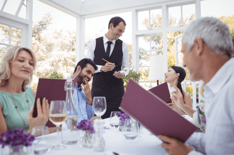 People in restaurant, smiling waiter